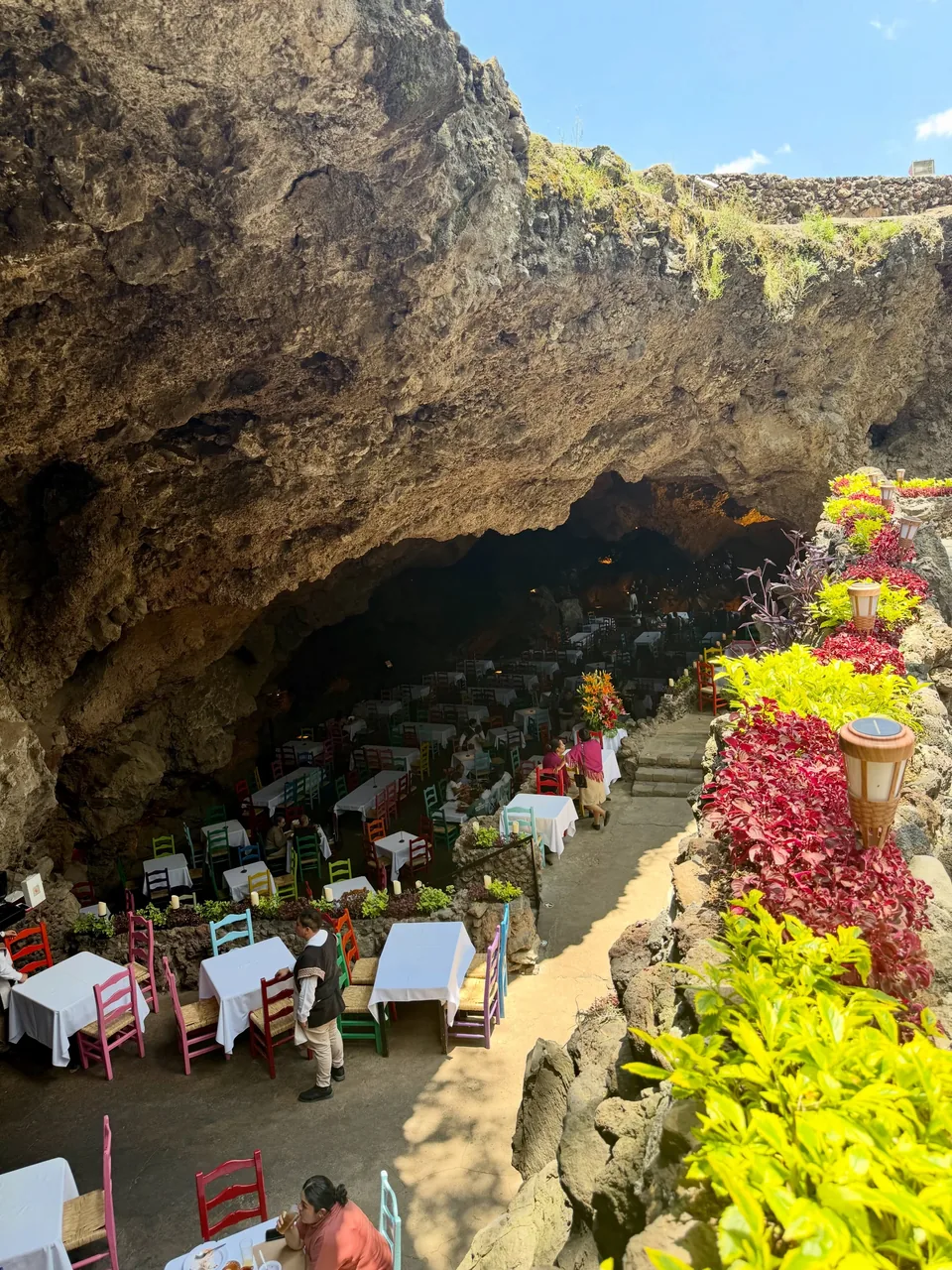 The mouth of the grotto at La Gruta Teotihuacan, with the dining room below and flowers on the rock