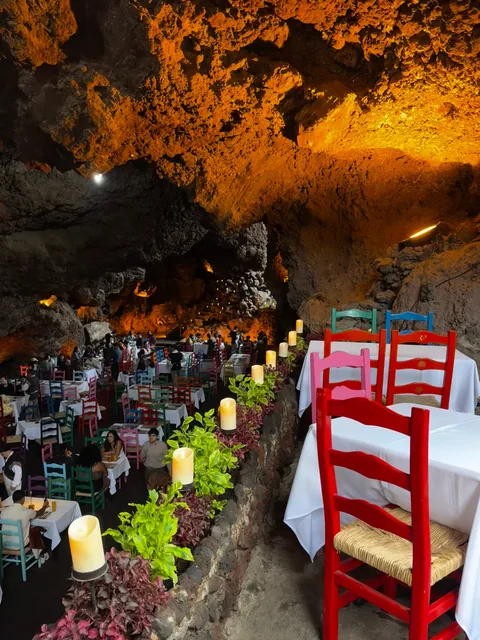 A table with candles and red chairs at La Gruta Teotihuacan