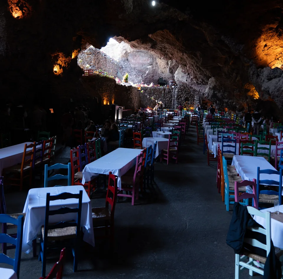 An aisle of white-clothed tables under the rock vault at La Gruta Teotihuacan